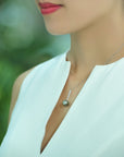 Model wearing a Qlassico pendant necklace from the Celestial Capsule, featuring a round peacock-coloured Tahitian pearl set in 18K white gold.
