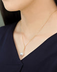 Model wearing a Qlassico pendant necklace from the Celestial Capsule, featuring a round Akoya pearl set in 18K yellow gold.