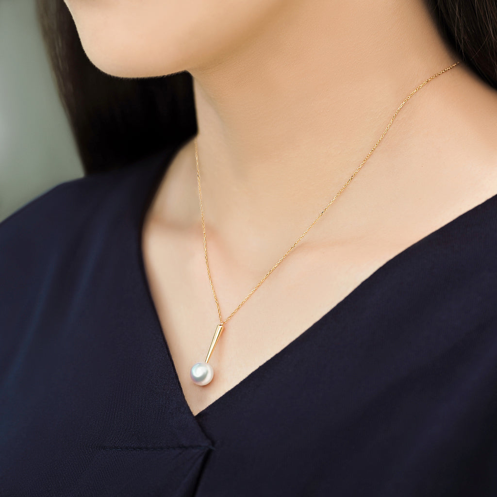 Model wearing a Qlassico pendant necklace from the Celestial Capsule, featuring a round Akoya pearl set in 18K yellow gold.