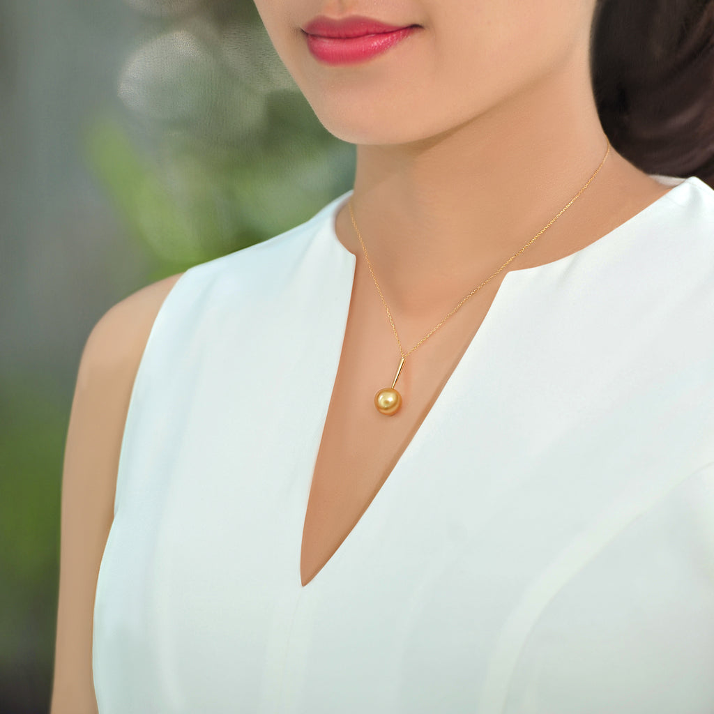 Model wearing a Qlassico pendant necklace from the Celestial Capsule, featuring a round golden South Sea pearl set in 18K yellow gold.