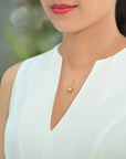Model wearing a Qlassico pendant necklace from the Celestial Capsule, featuring a round golden South Sea pearl set in 18K yellow gold.