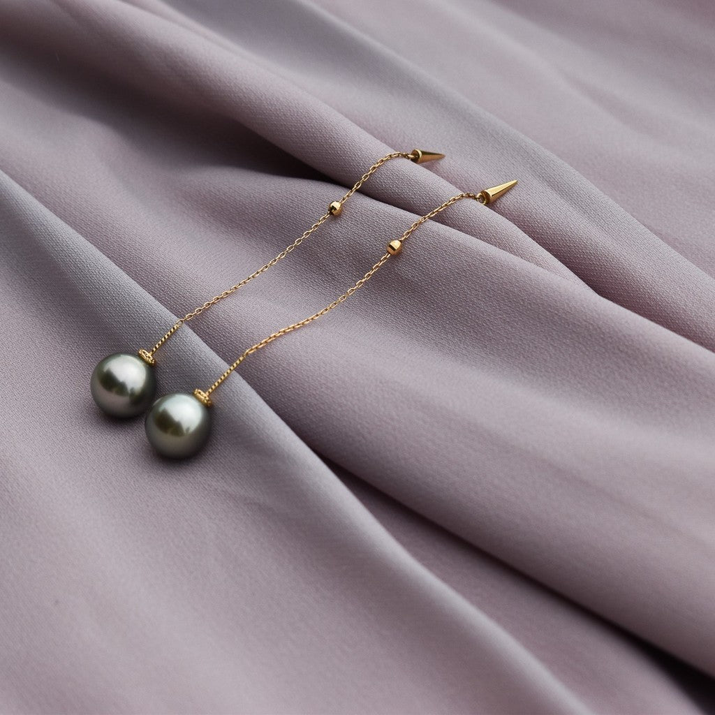 Qlassico dangling earrings from the  Celestial Capsule, featuring a pair of round grey-green Tahitian pearls set in 18K yellow gold.